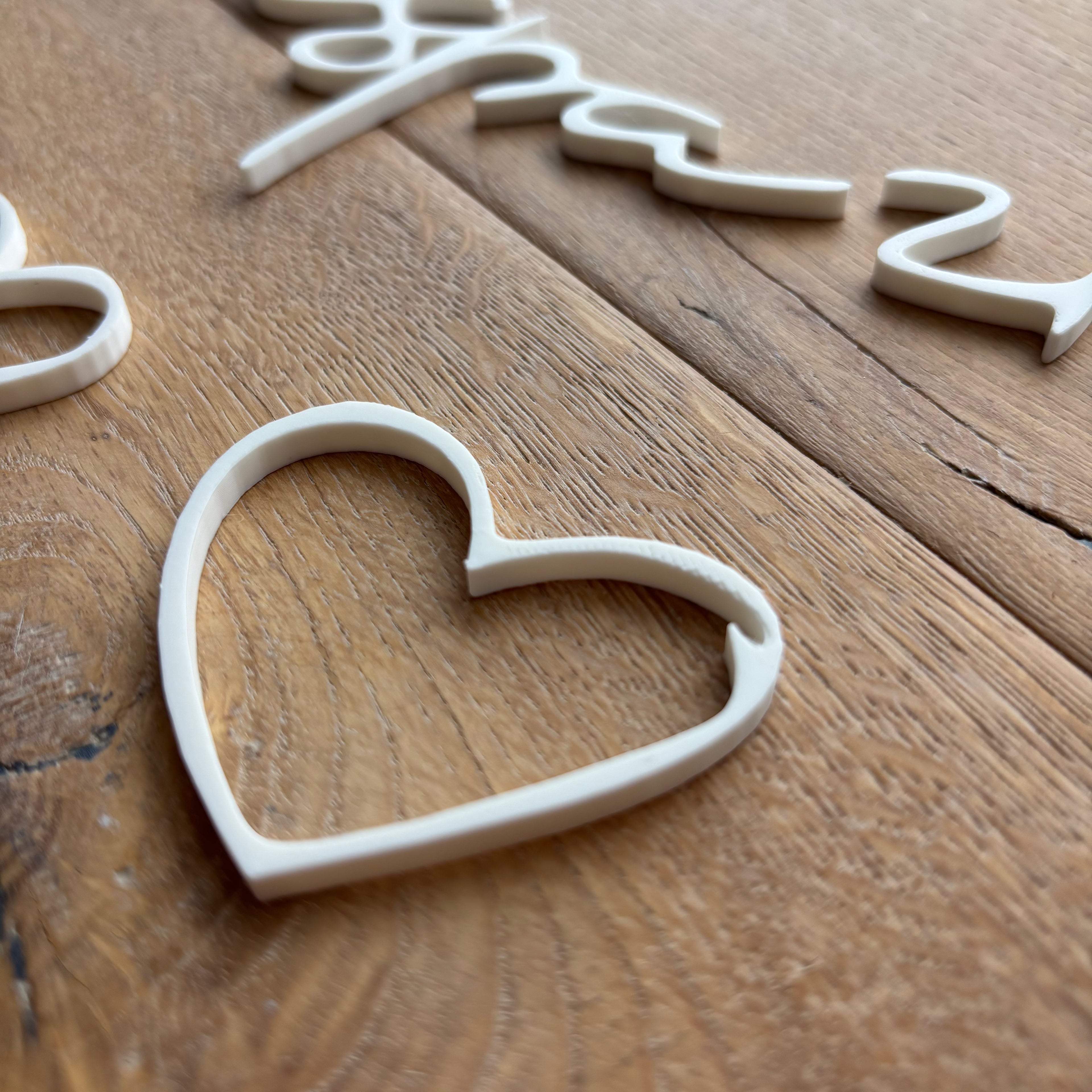 Weißes 3D-Herz aus PLA, minimalistisch gestaltet, liegend auf Holz.