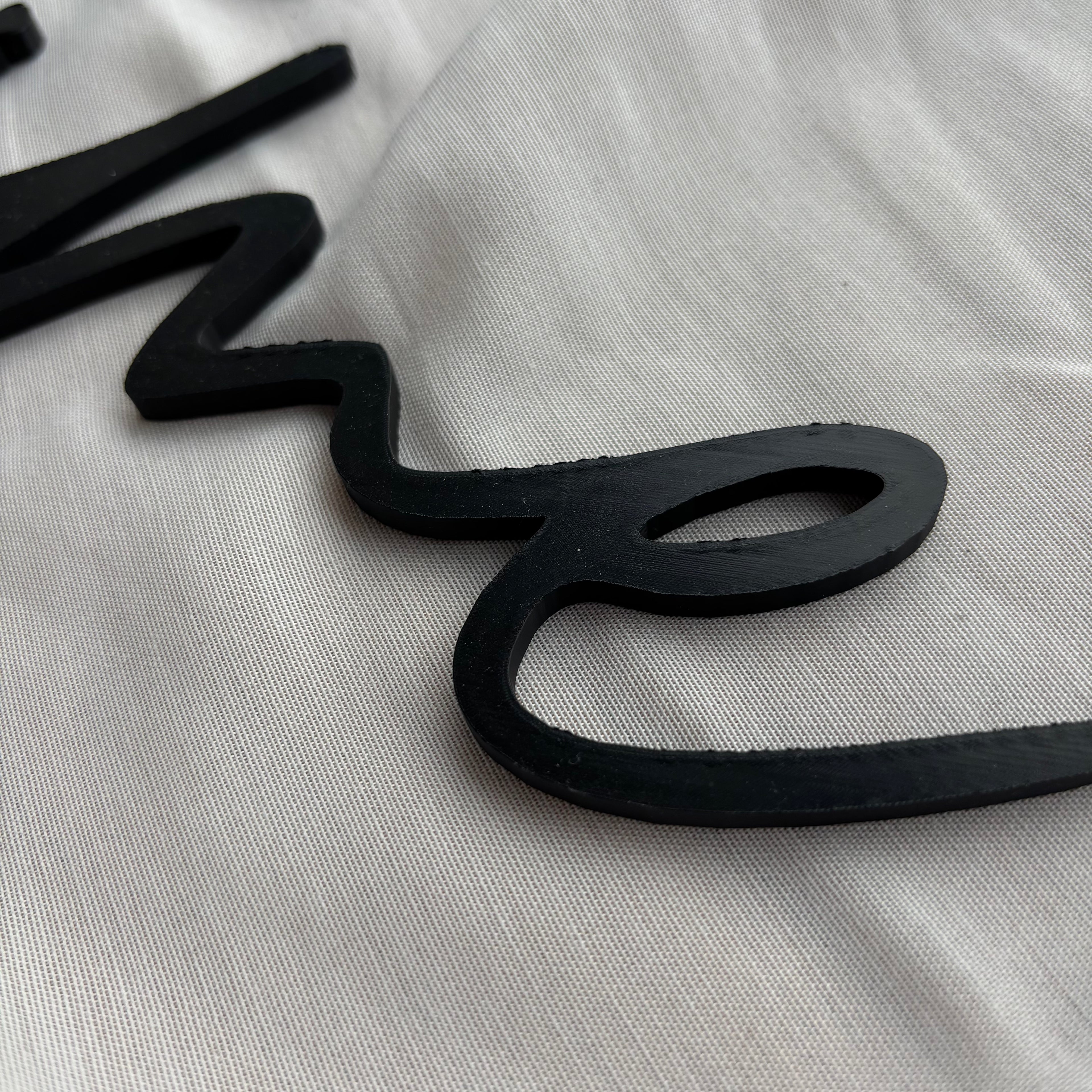 Nahaufnahme des schwarzen 3D-Schriftzuges „metime“ mit Fokus auf die hervorgehobenen Kanten und Struktur.